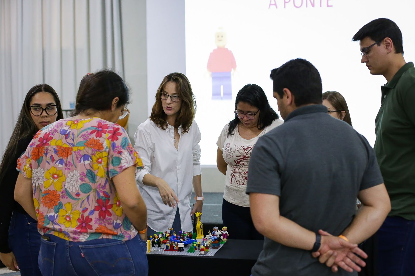 Natália conduzindo um grupo ao redor de um modelo coletivo