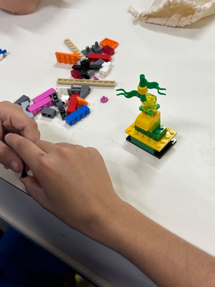 Mãos construindo um modelo de LEGO em silêncio sobre a mesa