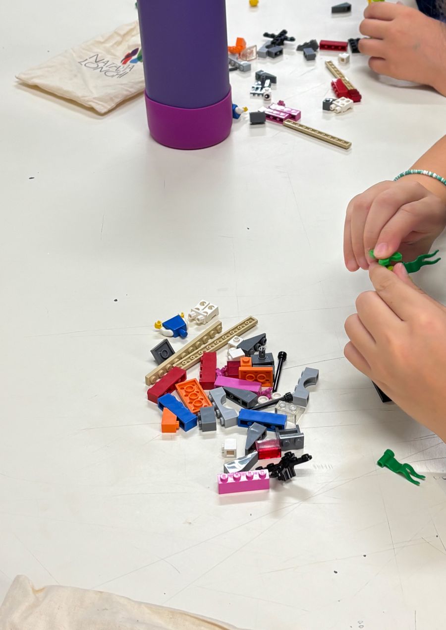 Mãos escolhendo peças de LEGO sobre uma mesa branca