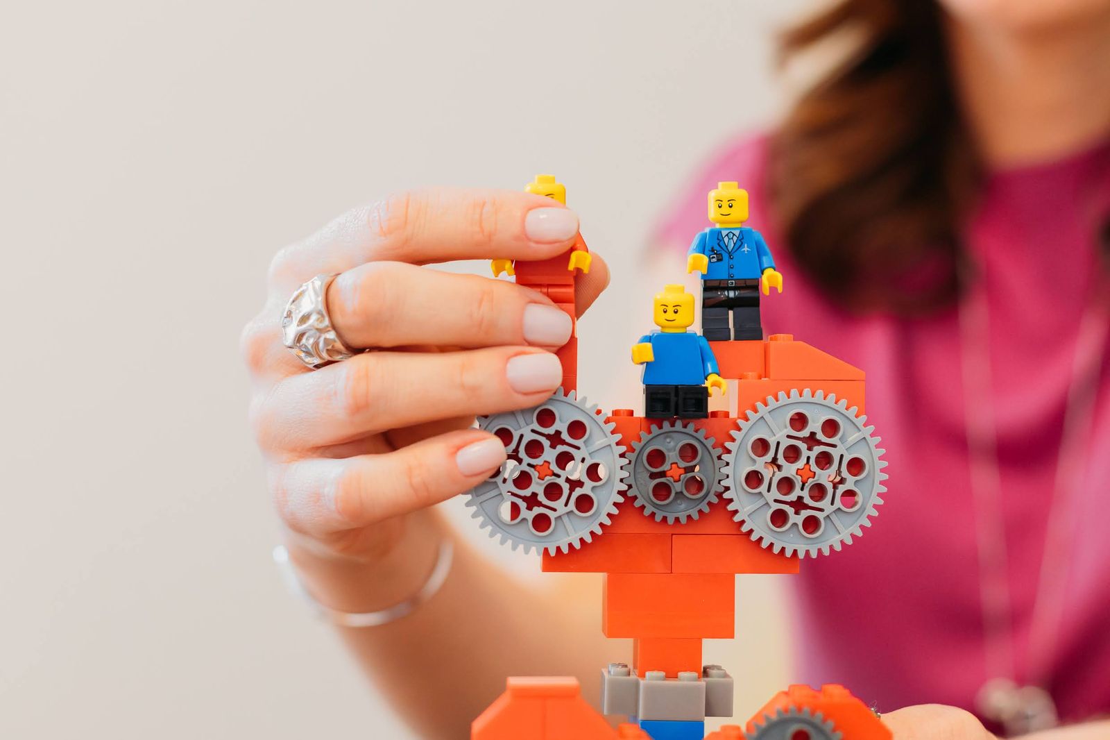 Mão encaixando uma engrenagem em um modelo de LEGO com dois bonecos